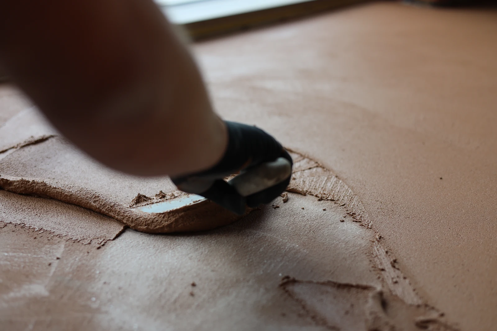 Craftsman hand-finishing the edge of an Odilon Carran floor